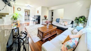 A spacious living room with a piano, a sofa, and a dining area in the background.