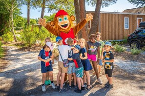 Um mascote em frente a um grupo de crianças ao ar livre.