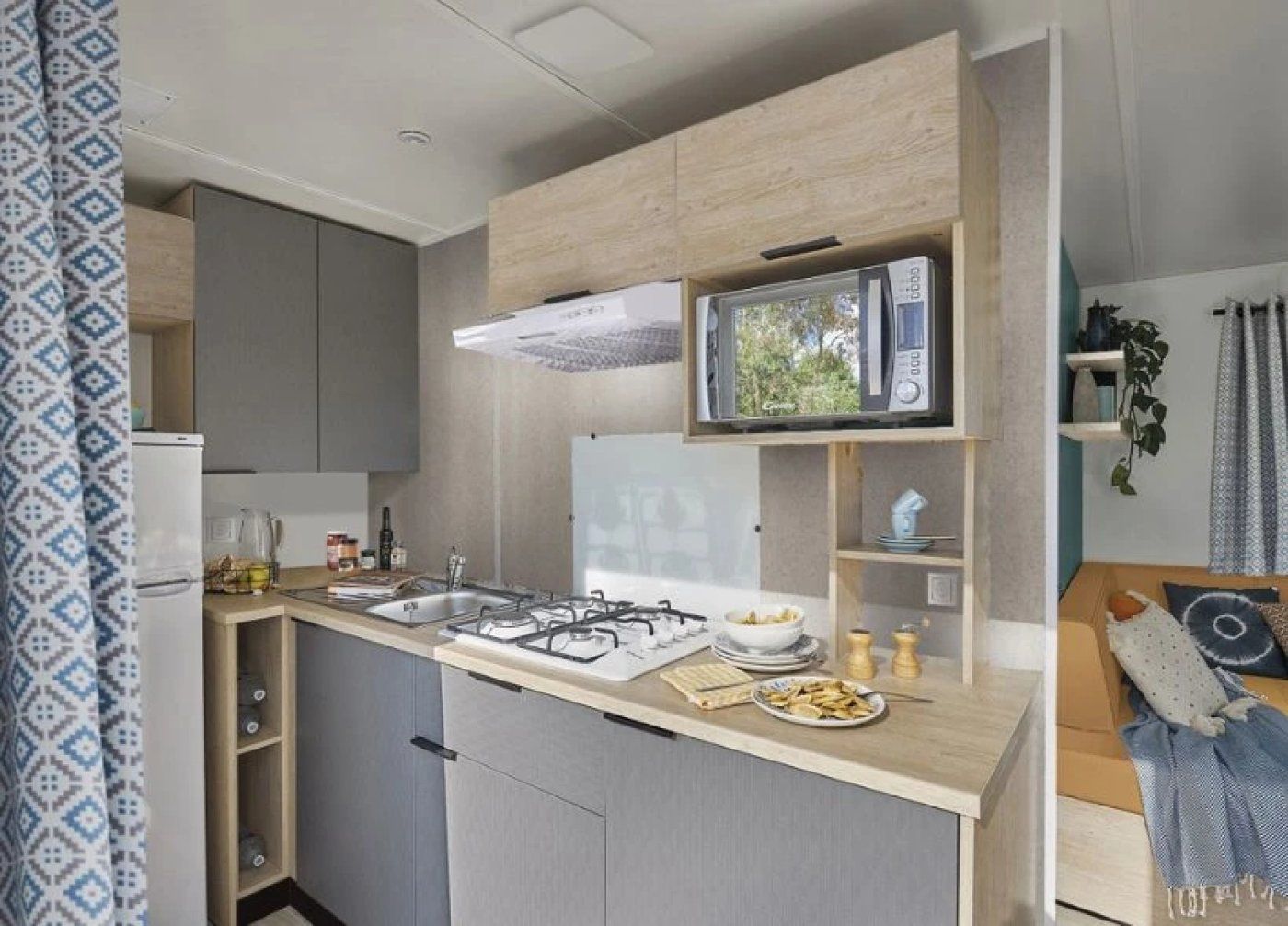 Una cucina compatta con forno a microonde integrato, piano cottura a gas e un piccolo frigorifero.