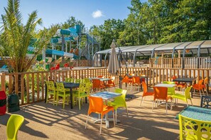 Enjoy al fresco dining in a serene outdoor setting with tables, chairs, and umbrellas.
