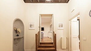 A wooden staircase leading to a second-floor landing with a white door and a radiator on the right. - Coppelle Charme - Three Bedroom Apartment, Sleeps 6 (Rome)