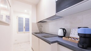 A modern kitchen with a built-in microwave, a coffee machine, and a kettle on the counter. - Coppelle Charme - Three Bedroom Apartment, Sleeps 6 (Rome)