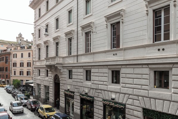 A historic building with a classic facade, multiple windows, and a street in front with parked cars.