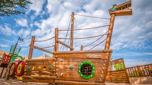 Een houten piratenschip speelconstructie met touwen en een stuurwiel.