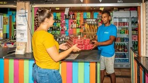 A bar area with a counter, shelves with bottles, and a refrigerator. - ZEcamping animé espace aquatique dog friendly locatif TV clim 4 pers (Argeles-sur-Mer)