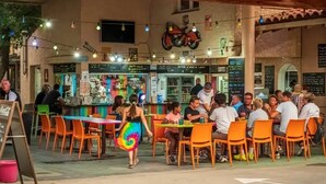An outdoor dining area with orange chairs and tables, a bar with a motorcycle decoration, and a chalkboard menu. - ZEcamping animé espace aquatique dog friendly locatif TV clim 4 pers (Argeles-sur-Mer)