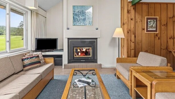 Una sala de estar con chimenea, televisor y sofá.
