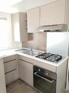 A modern kitchen with a gas stove, a sink, and a built-in oven. - ZEcamping 4* piscine chiens acceptés locatif clim 34m2 8 pers (Monoblet)