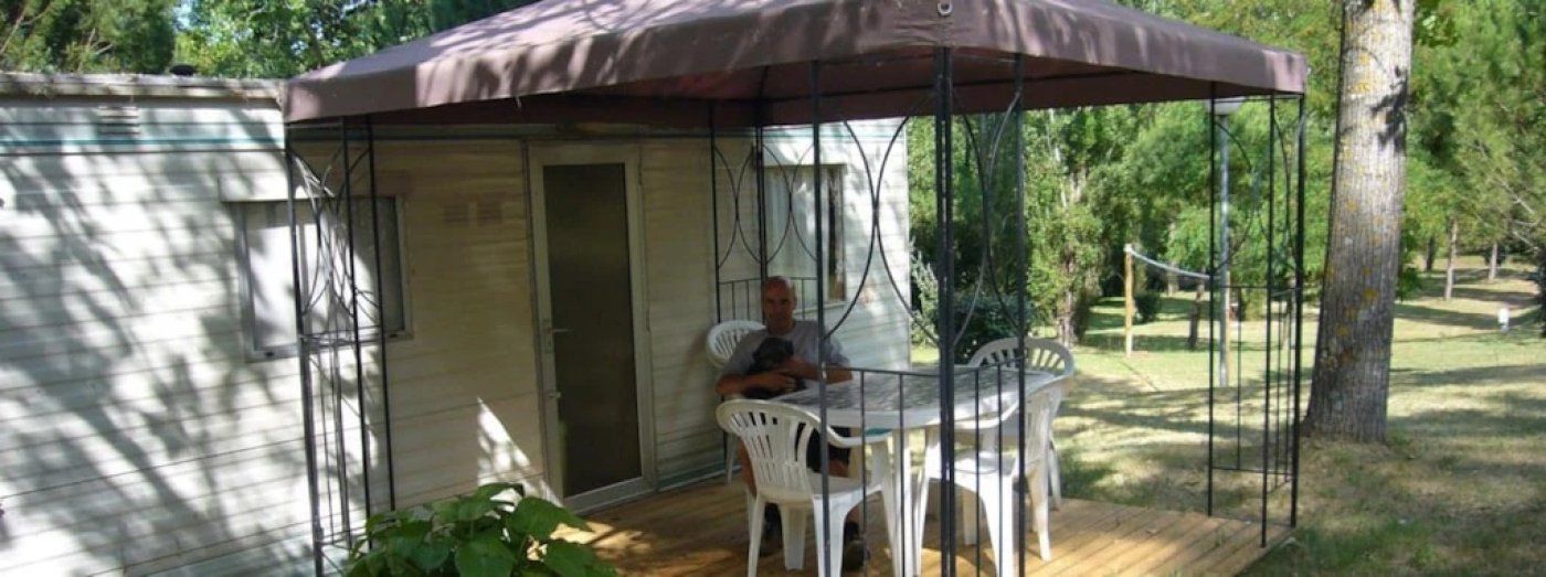 Un espace extérieur abrité, avec une table et des chaises, une petite porte et une terrasse en bois.