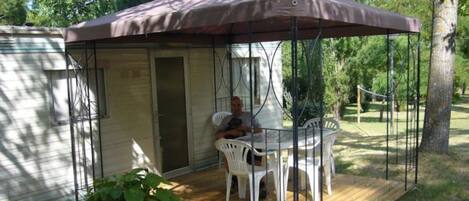 Un espace extérieur abrité, avec une table et des chaises, une petite porte et une terrasse en bois.