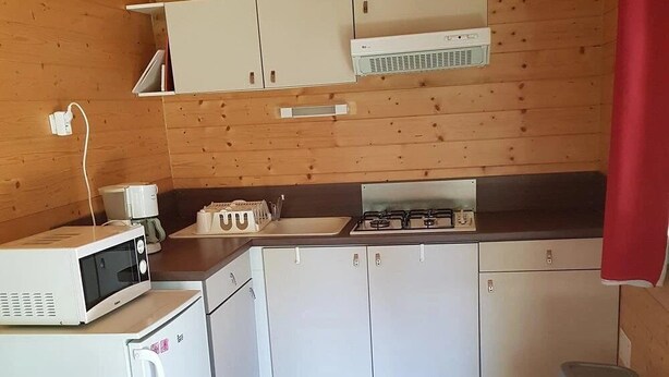 Cozinha compacta com micro-ondas, fogão e armários.