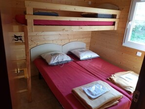 Un lit superposé avec un matelas rouge, des oreillers et une échelle en bois.
