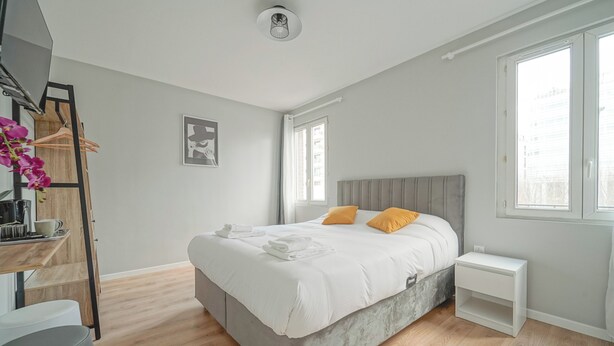 A modern bedroom with a bed, bedside tables, and a window. - Hôtel Trianon Saint Ouen (Saint-Ouen)