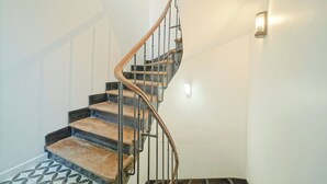 A spiral staircase with wooden steps and metal railings in a room with white walls and a patterned floor. - Hôtel Trianon Saint Ouen (Saint-Ouen)