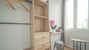 A room with a wooden wardrobe, a small table with a potted plant, and a window with curtains. - Hôtel Trianon Saint Ouen (Saint-Ouen)