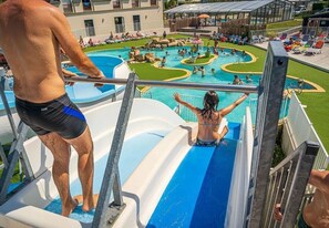 A water slide at a resort with multiple pools and lounge areas.