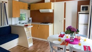 Eine kompakte Küche mit Essbereich, Holzschränken, einem Einbauherd und einem Kühlschrank.