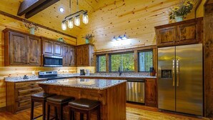 Una cocina amplia con armarios de madera, un refrigerador de acero inoxidable y una encimera de granito.