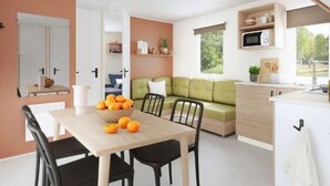 A modern living space with a dining area, a green sofa, and a kitchen with a microwave.