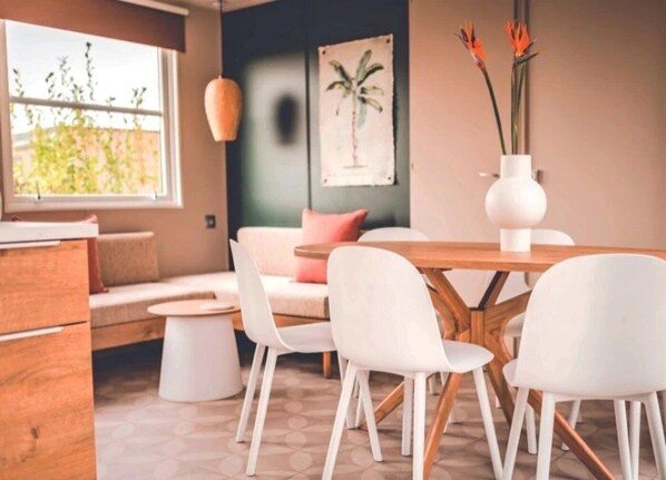 A modern dining area with a wooden table, white chairs, and a vase with flowers.