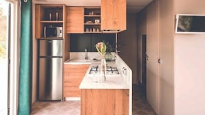 Una cocina moderna con armarios de madera, un refrigerador de acero inoxidable y una estufa a gas.