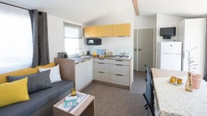 A compact living space with a sofa, coffee table, kitchenette, and a dining area.
