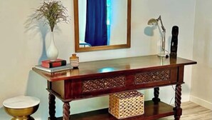 A wooden console table with a mirror, books, a lamp, and decorative items. - Hacienda East - Central + Bright + Just Right (Austin)
