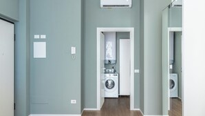 A laundry room with a washing machine and dryer, a door with a light switch, and a wall-mounted phone. - Pirandello 1 - Studio Apartment, Sleeps 2 (Milano)