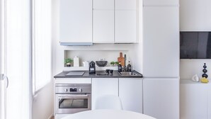 A modern kitchen with white cabinets, a black countertop, stainless steel appliances, and a window providing natural light. - Pirandello 1 - Studio Apartment, Sleeps 2 (Milano)