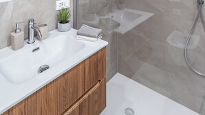 A modern bathroom with a glass-enclosed shower, a white sink, and a wooden vanity. - Pirandello 1 - Studio Apartment, Sleeps 2 (Milano)