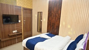 A bedroom with a bed, a TV mounted on the wall, a wardrobe, and a mirror. - Hotel A.D. Residency By Reverie (Agra)