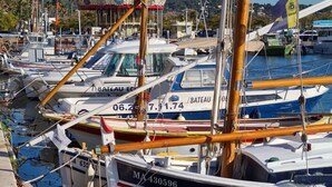 Un port de plaisance avec plusieurs bateaux amarrés, une jetée en bois et, au fond, un bâtiment rouge et blanc.