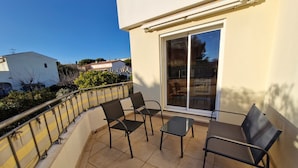 Un balcon avec une porte-fenêtre, deux chaises et une petite table.