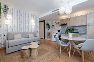 A modern living room with a grey sofa, round coffee table, and a dining area with a round table and chairs.