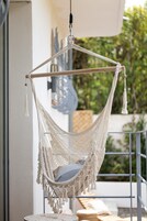 A white macrame hammock chair hanging from a balcony railing.