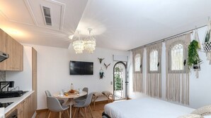 A modern, well-lit room with a dining area, a bed, and a kitchen. - Garden Apartment La Bohémienne, Mandara Beach (Antibes)