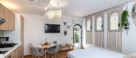 A modern, well-lit room with a dining area, a bed, and a kitchen.