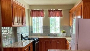 A kitchen with wooden cabinets, a stove, a sink, and a refrigerator.