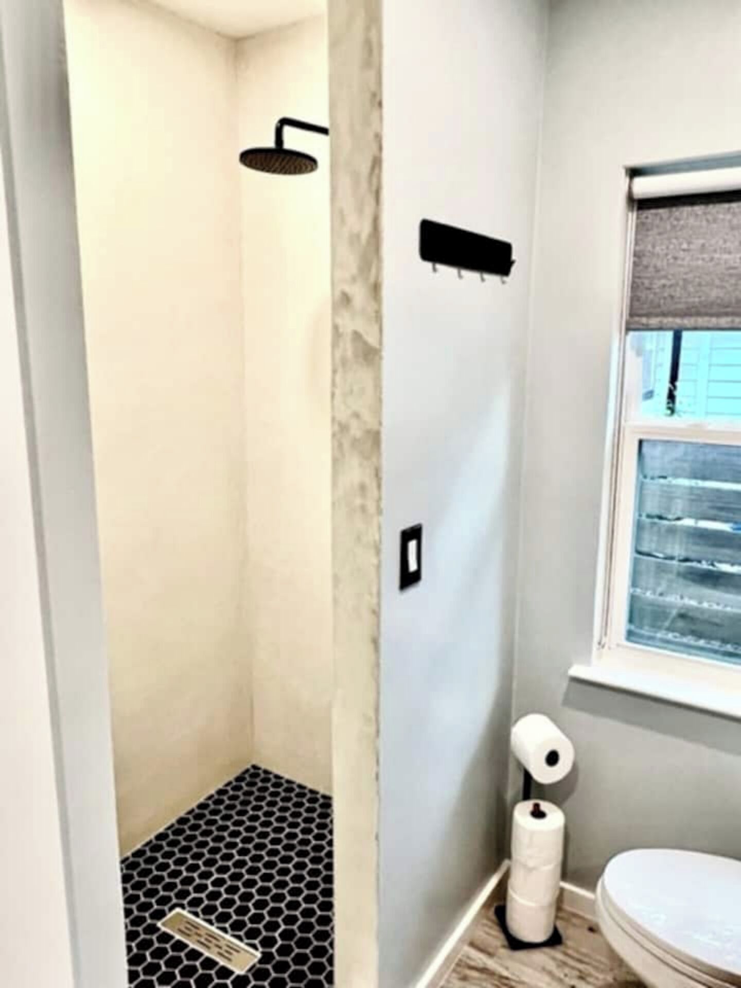 Un baño con ducha, inodoro y ventana.
