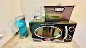 Un four à micro-ondes, un distributeur d’eau et un panier sur un plan de travail.