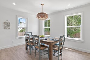 A dining room with a wooden table, six chairs, and a hanging light fixture. - Jini Jim Jams (Santa Rosa Beach)