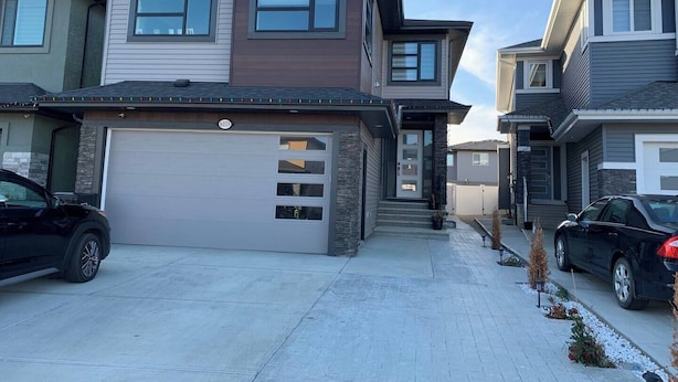 A modern two-story house with a garage, a driveway, and a small garden area. - PRIVATE, QUIET, CLEAN LEGAL SUITE FULLY FUNISHED. NEAR DOWNTOWN &TRAIN STATION (Edmonton)