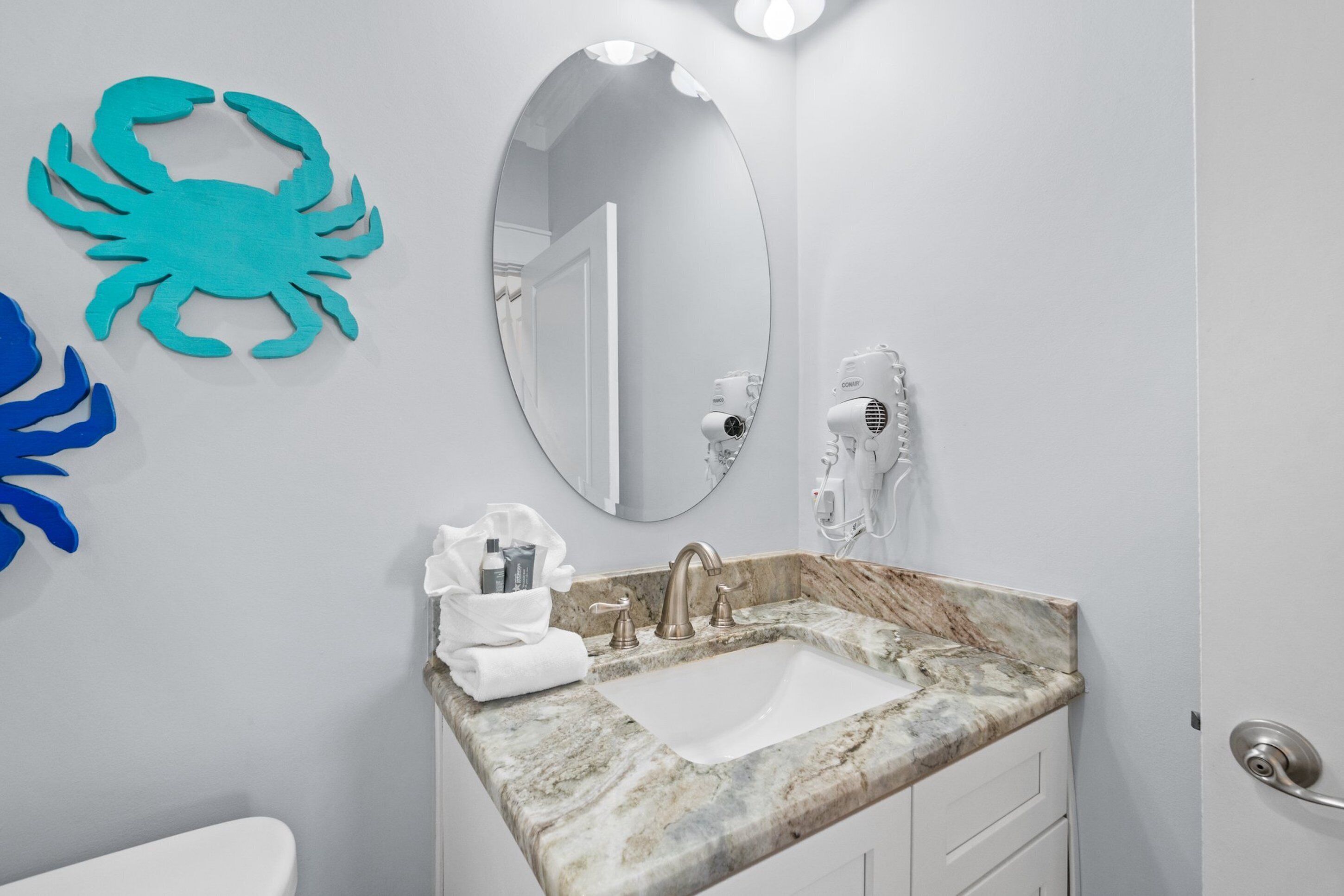 A bathroom with a marble sink, a large mirror, and a towel rack with toiletries.