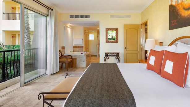 Una camera d'albergo con un letto, una scrivania, una sedia, un bagno e un balcone con vista.