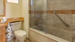 Un bagno con doccia vetrata, un water e un lavabo con piano.