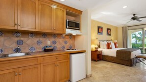 Cucina con mobili in legno, forno a microonde e frigorifero bianco.