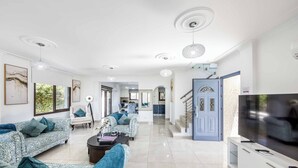 A spacious living room with a large TV, two sofas with patterned upholstery, and a coffee table.