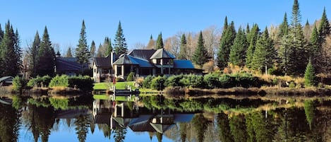 A lakeside property with a house, dock, and reflection in the water.