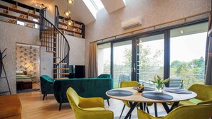 Een modern interieur met een wenteltrap, een eethoek met gele stoelen en een groot raam met uitzicht op groen.