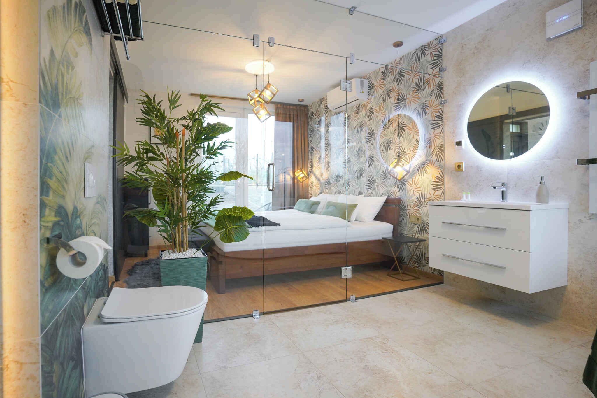 A modern bathroom with a toilet, sink, and a bed with a glass partition.